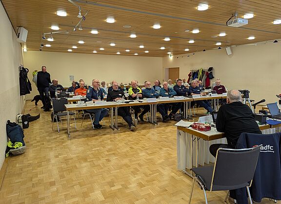 In einem Raum sitzen viele Personen, die angeregt diskutieren
