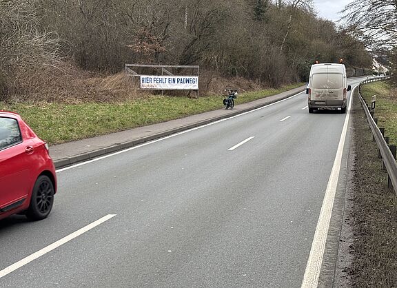 Banner "Hier fehlt ein Radweg" an der B8 bei Niederbrechen