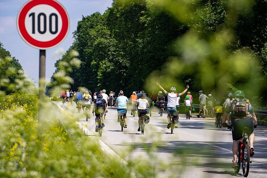 Symbolbild: Sternfahrt Berlin Radfahrer bei Sternfahrt neben Schild zu Geschwindigkeitsbegrenzung 100h/km